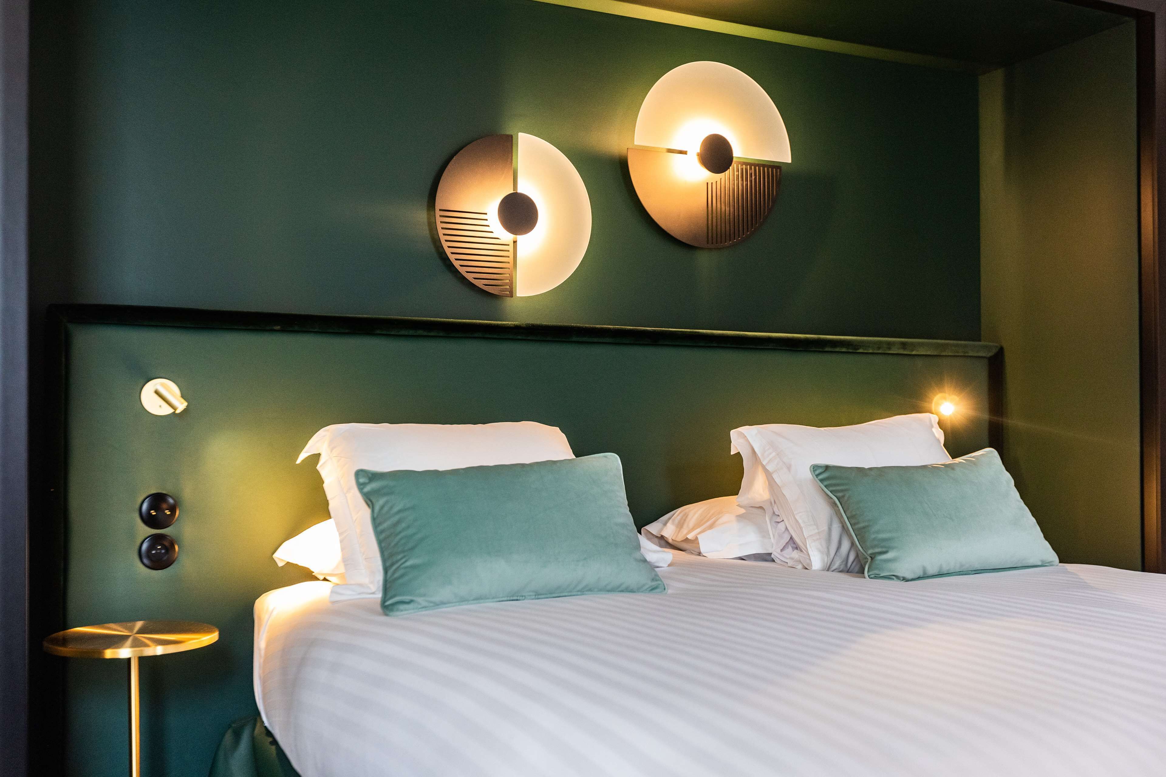 Een hotelkamer met een groot bed, twee nachtkastjes en wandlampen.