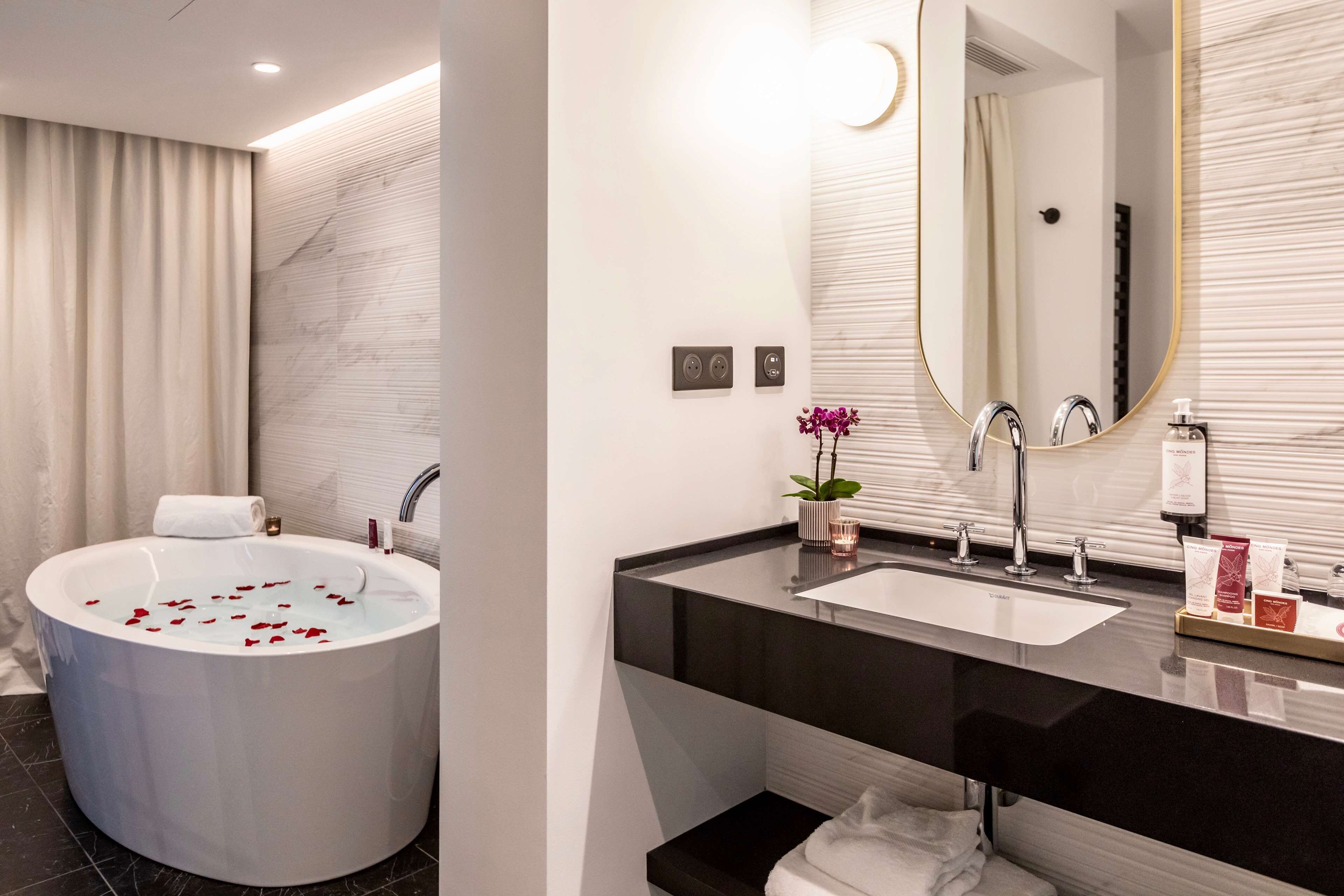 A modern bathroom with a freestanding bathtub, a large mirror, and a vanity with a sink and countertop.