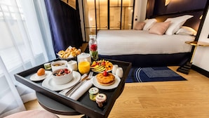 A hotel room with a neatly made breakfast tray on a table, a bed with pillows, a nightstand, and a view of the room's interior. - Best Western Plus Crystal, Hotel & Spa (Nancy)
