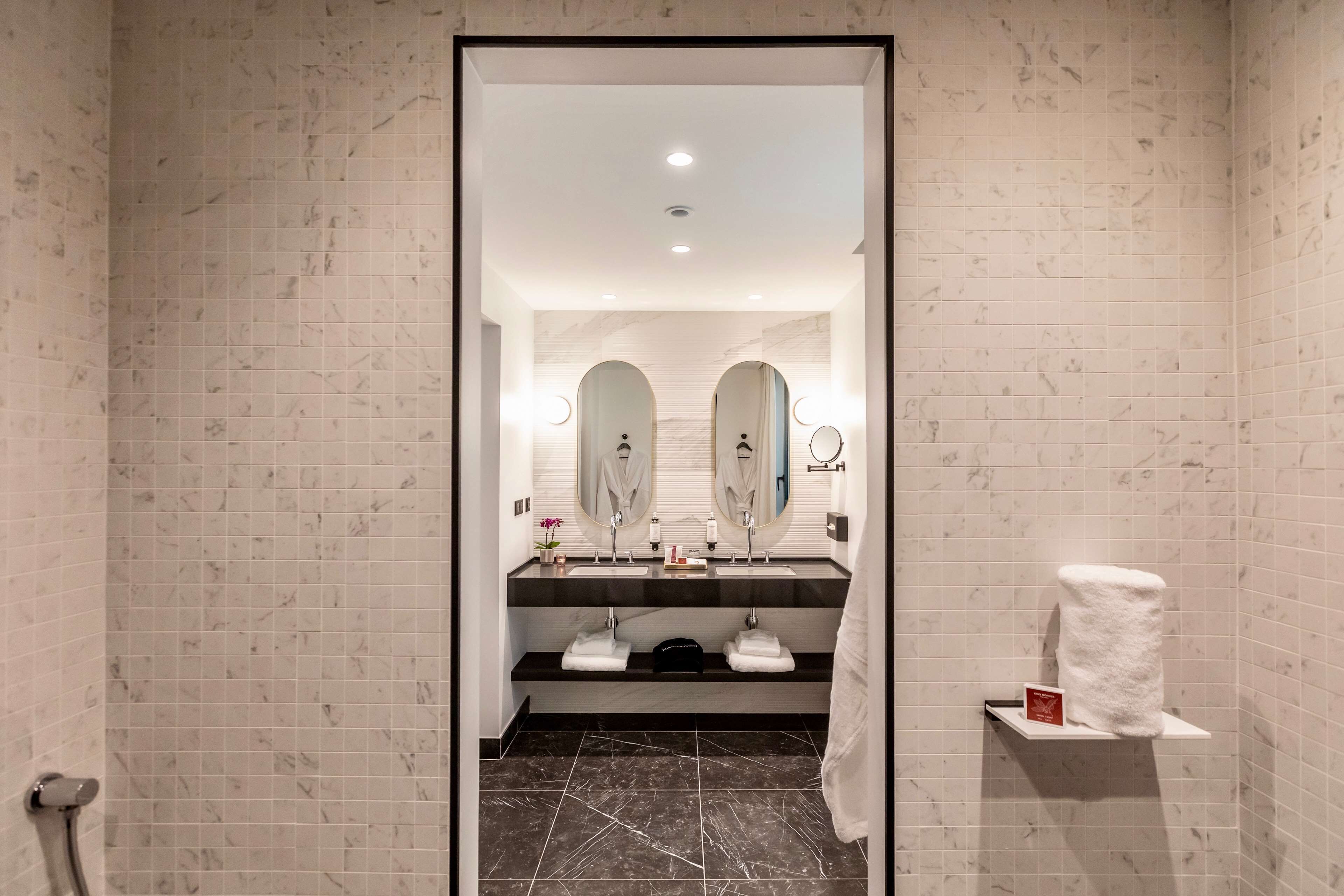 A modern bathroom with two sinks, a mirror, and a towel rack.