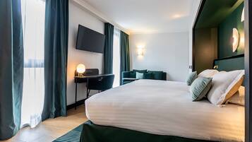 Une chambre d’hôtel avec un grand lit, un bureau avec une chaise, un téléviseur à écran plat fixé au mur et une fenêtre avec des rideaux.