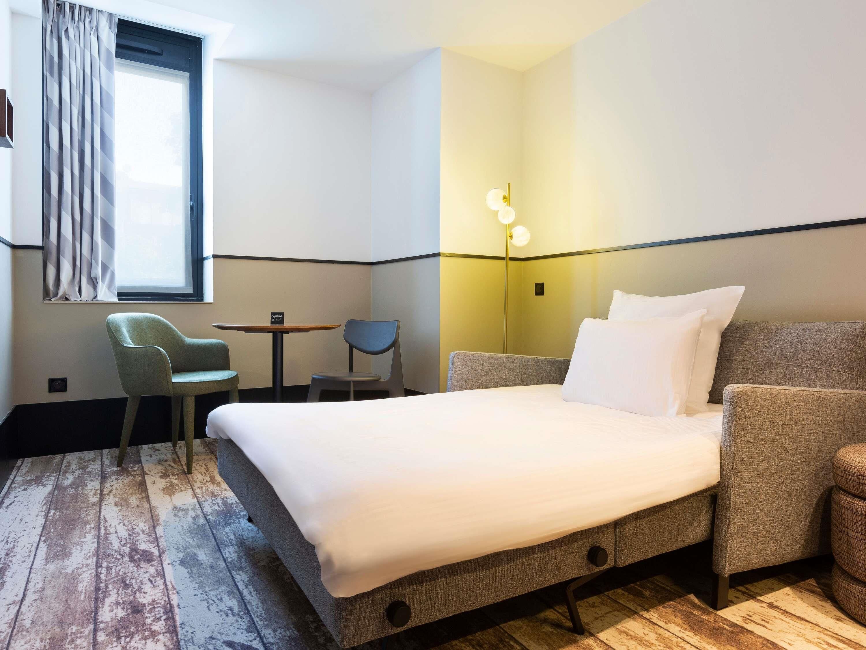 Habitación de hotel con cama, escritorio, silla y lámpara.