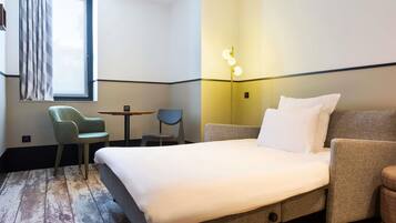 Habitación de hotel con cama, escritorio, silla y lámpara.