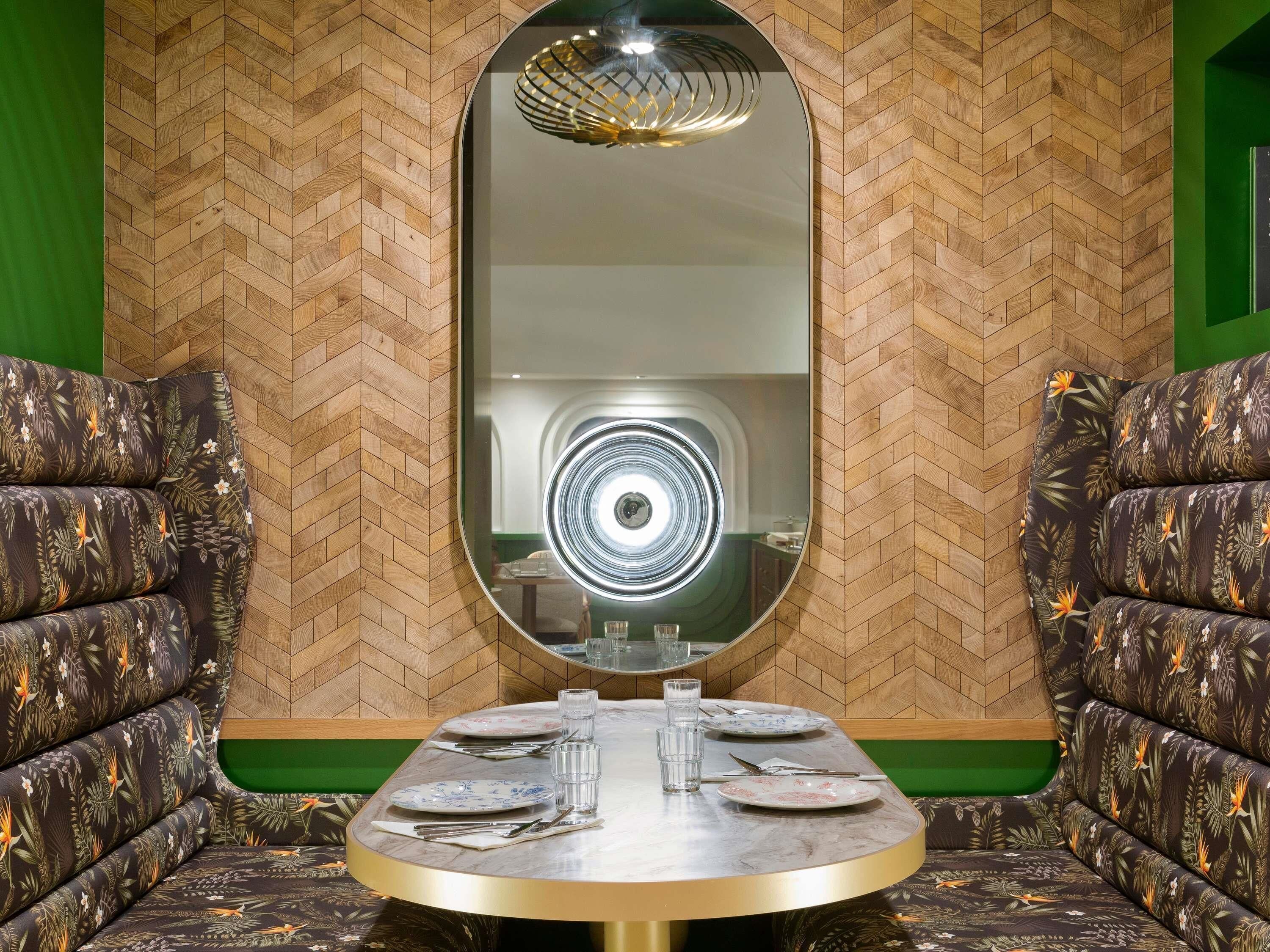 A dining area with a round table, chairs, and a large mirror on the wall.