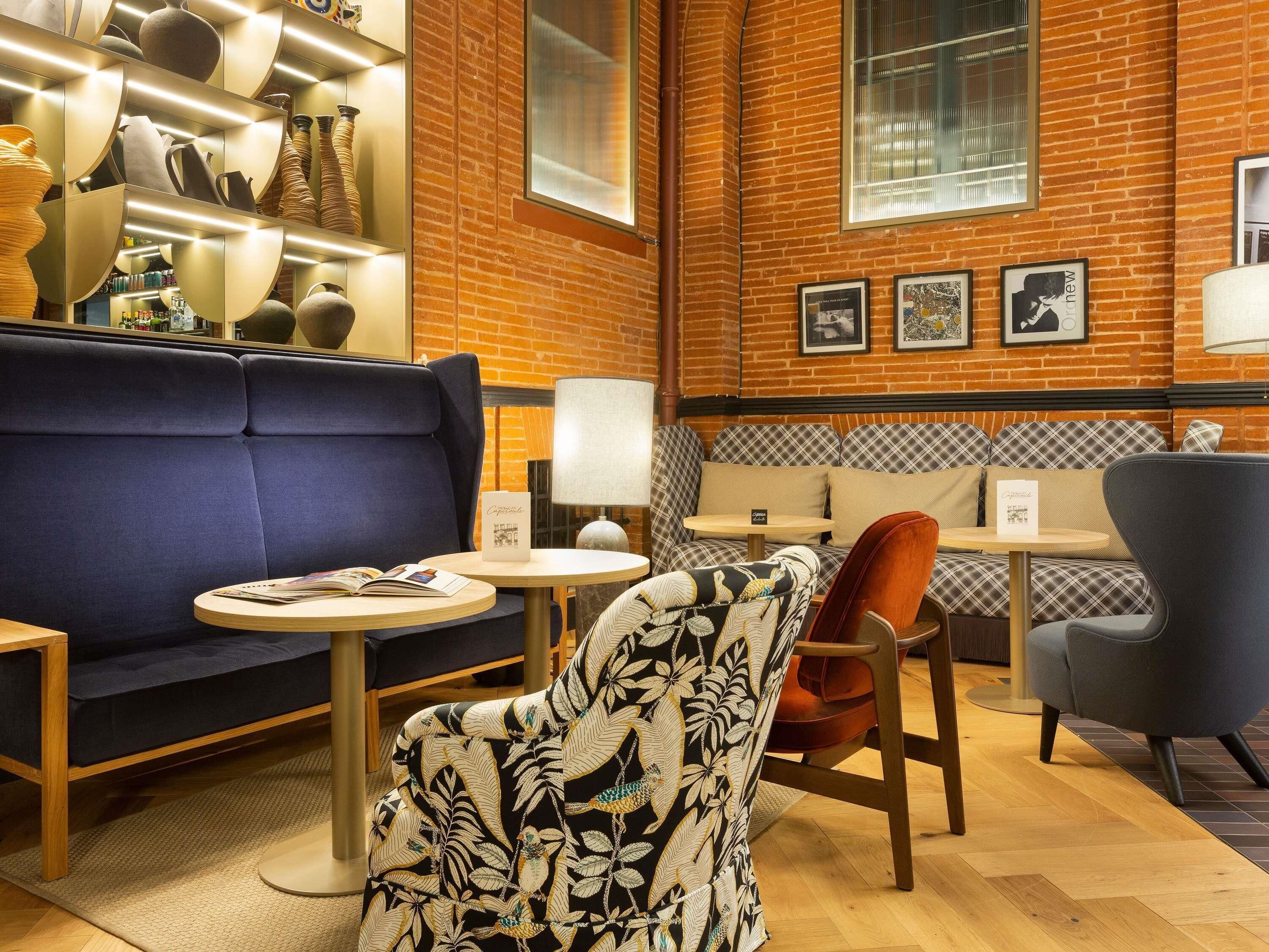 A cozy seating area with a blue sofa, patterned armchair, and a small round table.