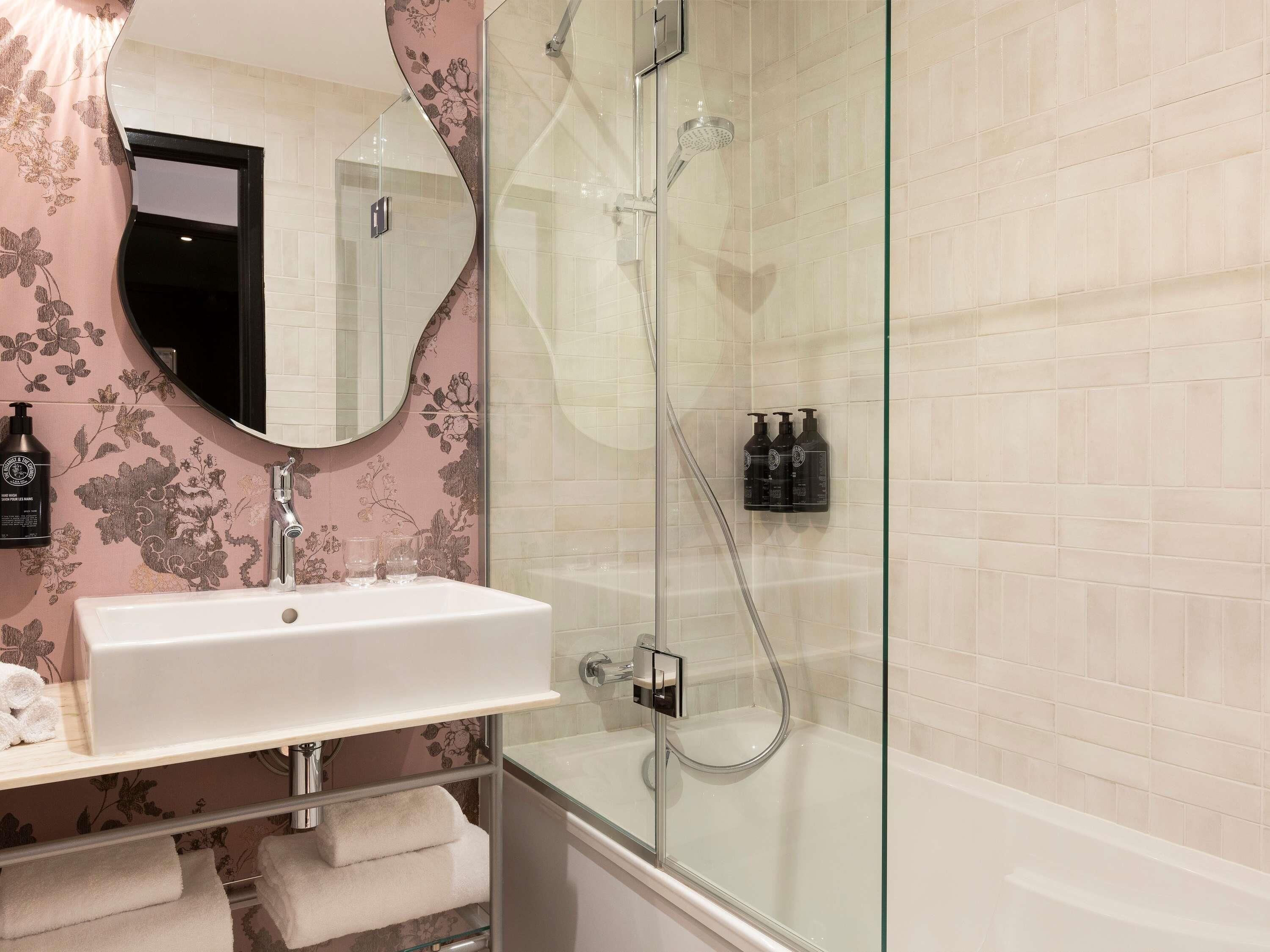 Une salle de bain avec une douche à parois de verre, un lavabo blanc et un miroir.