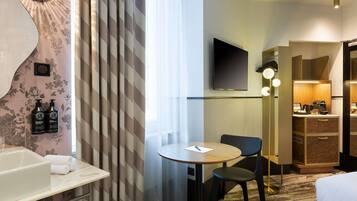 Een hotelkamer met een badkamer, een eethoek en een kitchenette.