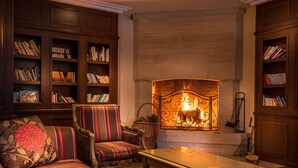 A cozy living room with a fireplace, striped sofas, and bookshelves filled with books.
