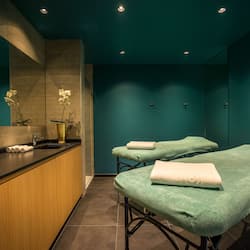 Relax in a serene spa room with two massage tables, a reception desk, and a large mirror.