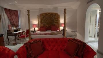 Un dormitorio con cama con dosel, un sofá tapizado rojo y un escritorio con silla.