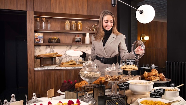 A buffet setup with various food items and a person serving. - Maison 46 (Paris)