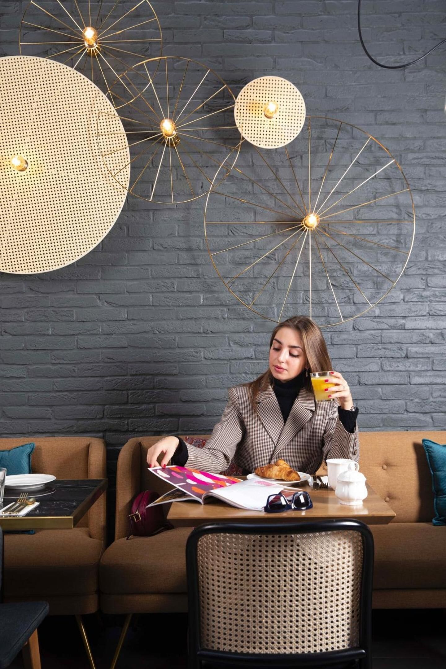 A person sitting on a brown sofa with a table in front of them, holding a glass of orange juice.