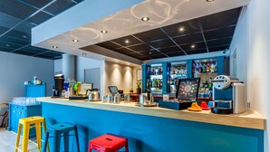 Un espace bar avec des tabourets, une machine à café et un comptoir.