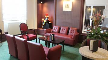 Un vestíbulo de hotel con un conjunto de sofá rojo, una mesa de centro de madera y una mesa redonda con un libro.