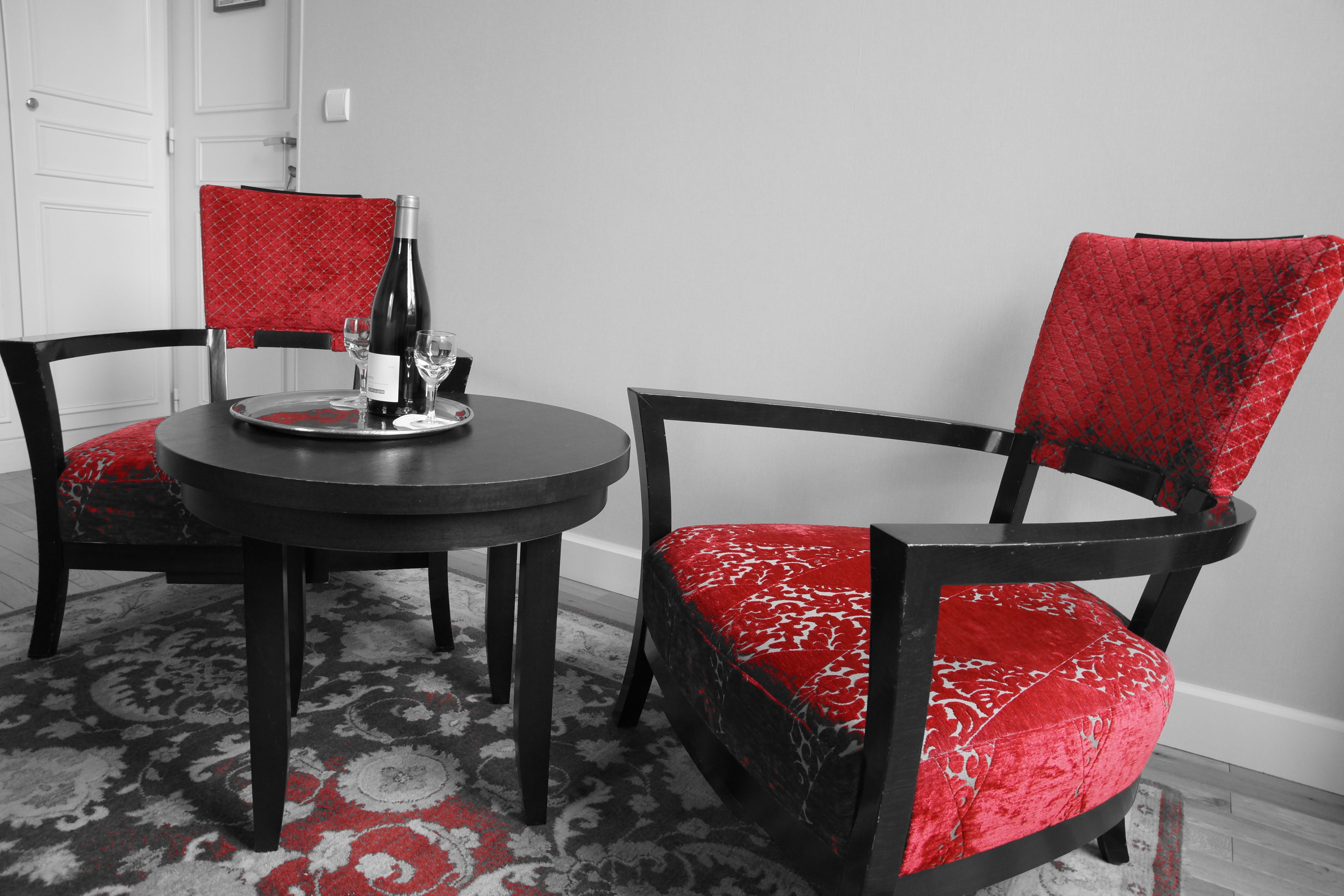 Un comedor con una mesa redonda, dos sillas, una botella de vino y copas.