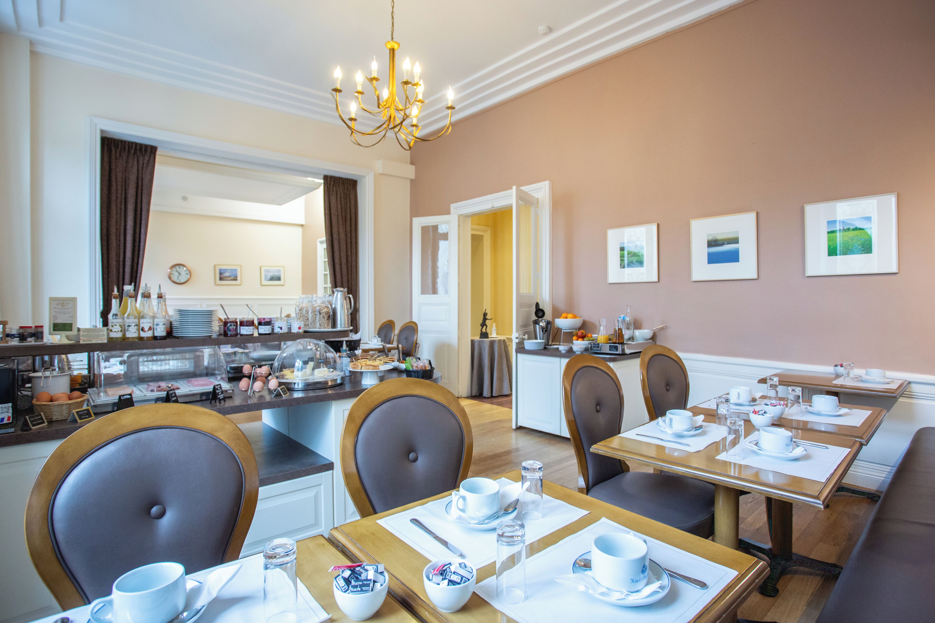 Un espace repas avec des tables préparées pour le petit-déjeuner, un coin café et une vue sur la cuisine.