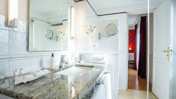 A modern bathroom with a granite countertop, a large mirror, and a towel rack.