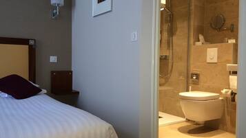 Habitación de hotel con cama, ducha y váter.