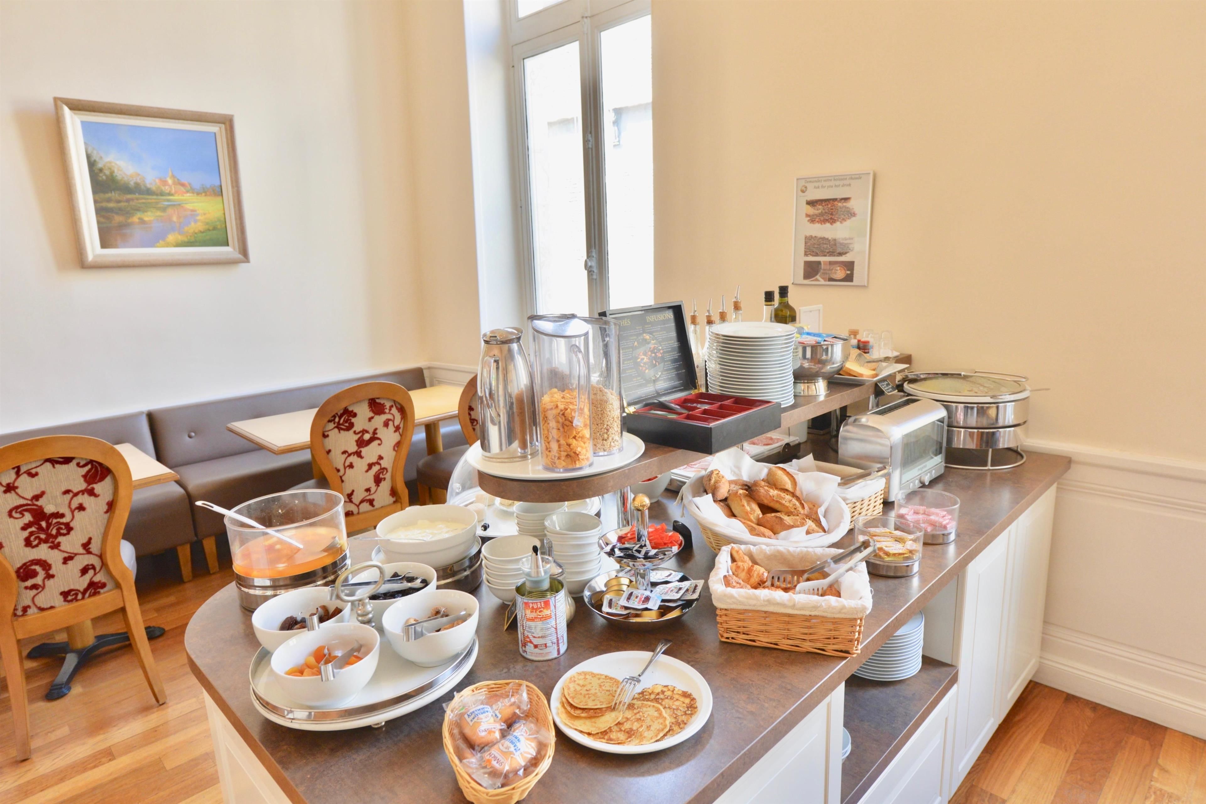 A breakfast buffet with various food items, a coffee station, and seating arrangements.