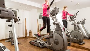 Une salle de sport équipée de tapis de course, d’appareils d’exercice et dotée d’un plancher en bois.