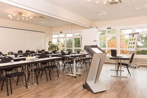 Une salle de conférence équipée de plusieurs tables, de chaises et d’un écran de présentation.