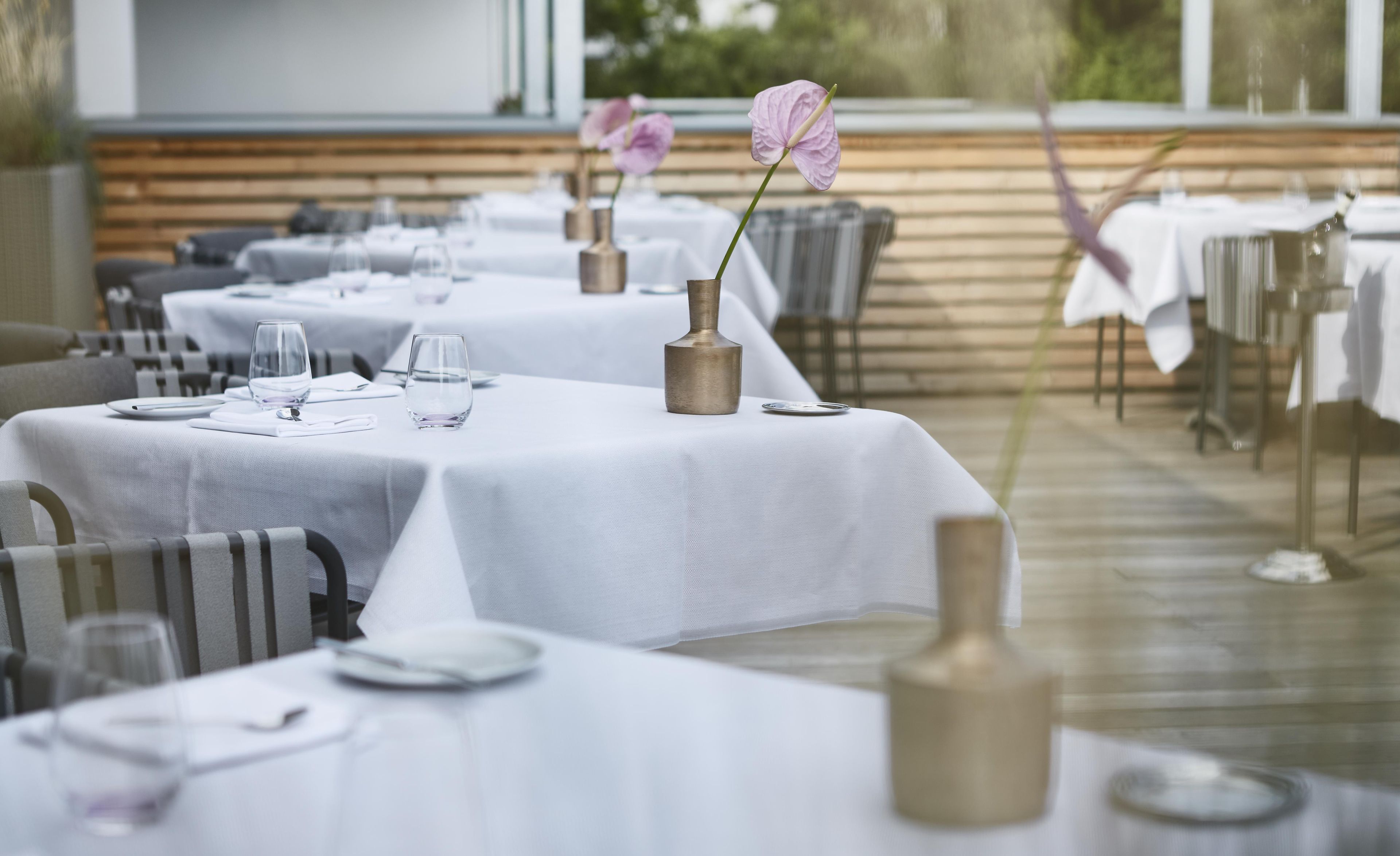 A restaurant with tables set for dining, featuring white tablecloths and silverware.
