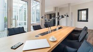 Une salle de conférence moderne équipée d’une longue table, de chaises, d’un ordinateur portable, d’un téléphone intelligent et d’une tasse à café.