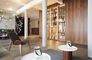 A modern interior with a bar area, wooden flooring, and a seating area with a chair and tables. - Scotty + Emily Hotel Ulm, Sure Hotel Collection by BW (Ulm)