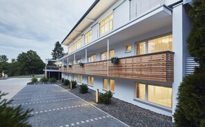 Un bâtiment moderne doté d’un toit plat, de nombreuses fenêtres et d’une terrasse en bois.