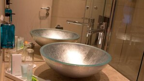Un baño con dos grandes cuencos de vidrio como lavamanos, una botella azul y una bandeja con artículos de aseo.