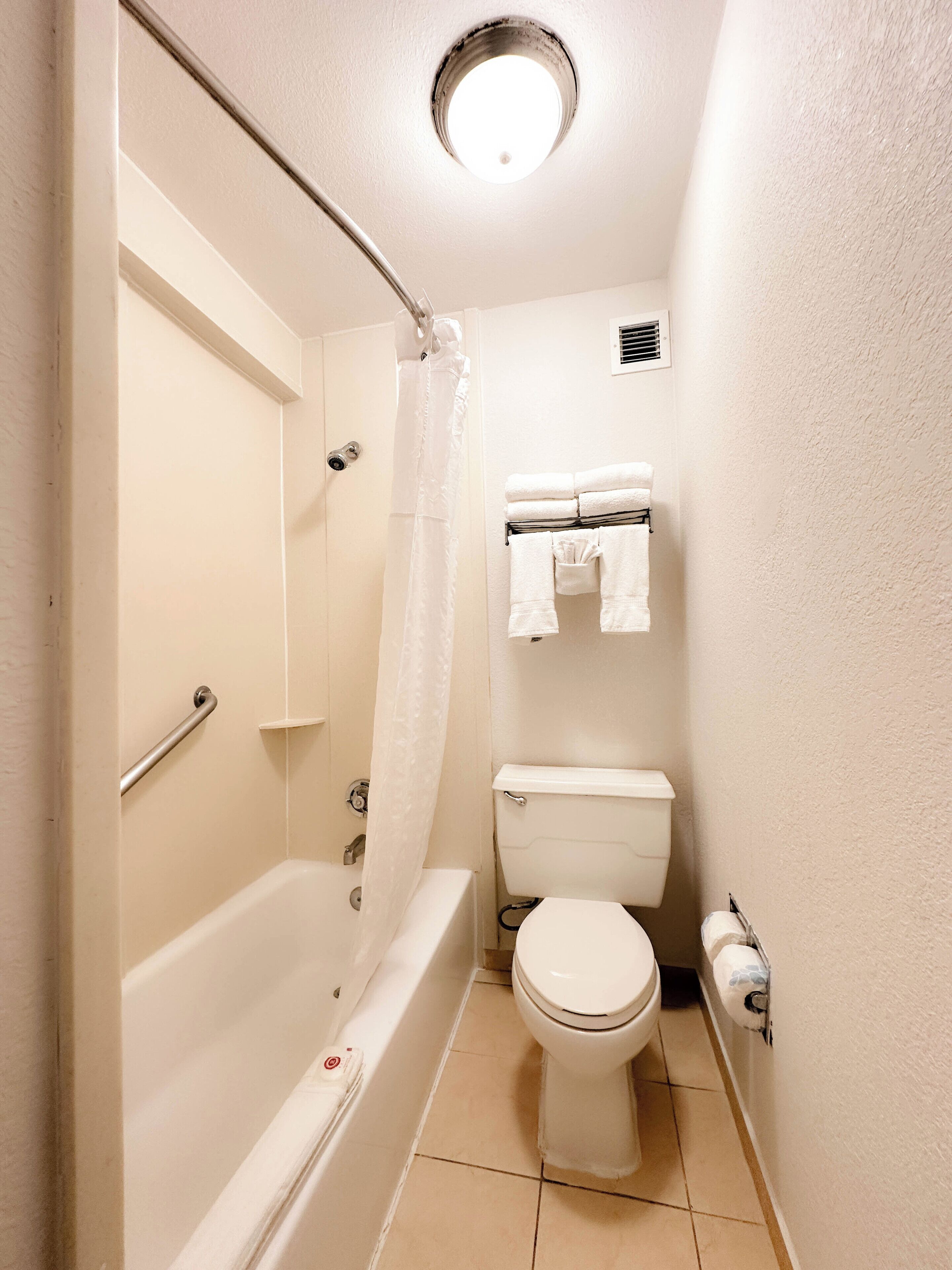Un baño pequeño y funcional con bañera, inodoro y zona de ducha.
