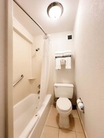Un baño pequeño y funcional con bañera, inodoro y zona de ducha.