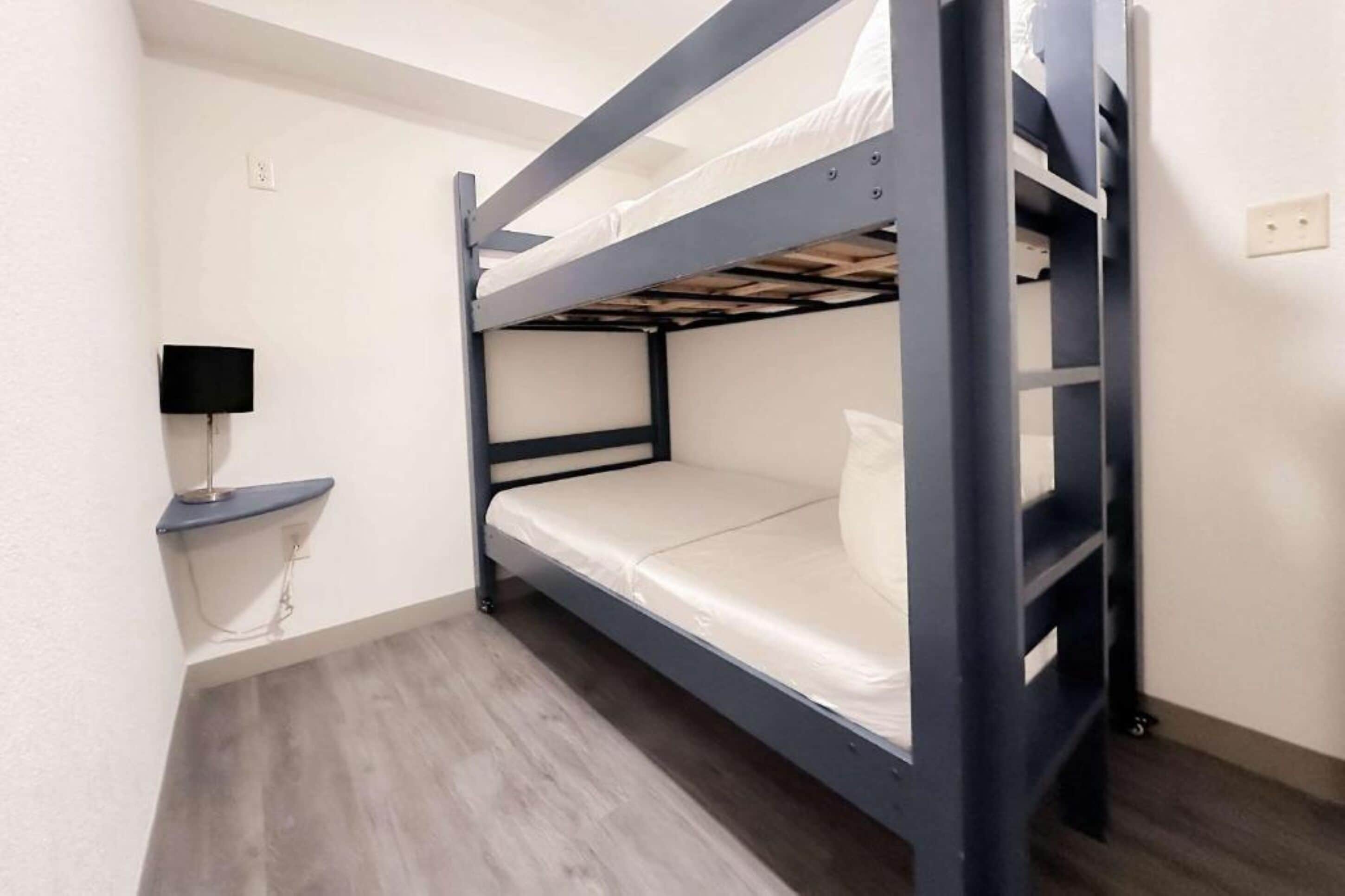 A bunk bed room with a desk and a lamp.