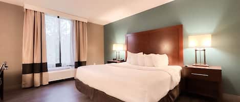 A hotel room with a large bed, two bedside tables with lamps, a window with curtains, and a radiator.