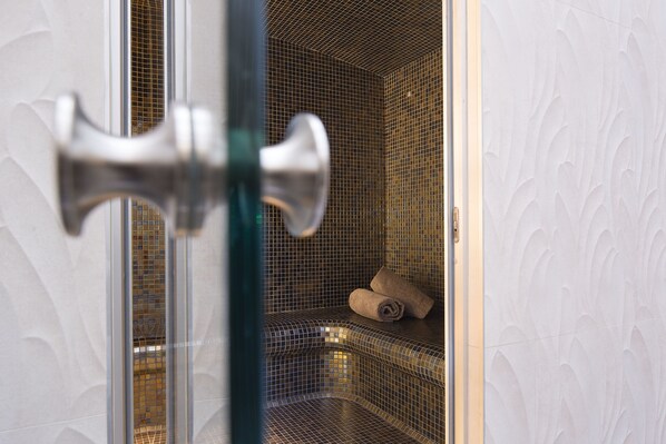 A bathroom with a tiled wall, a towel, and a door handle.