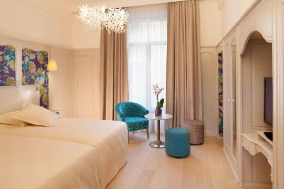 Una habitación de hotel con cama, una silla, una mesita y televisor.