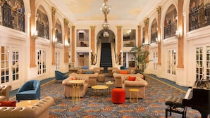 A grand lobby with ornate columns, a chandelier, and a piano. - Oceania L'Univers Tours (Tours)