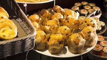 Un bufé con diversas opciones de panadería, como muffins y pasteles.