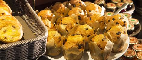Un bufé con diversas opciones de panadería, como muffins y pasteles.
