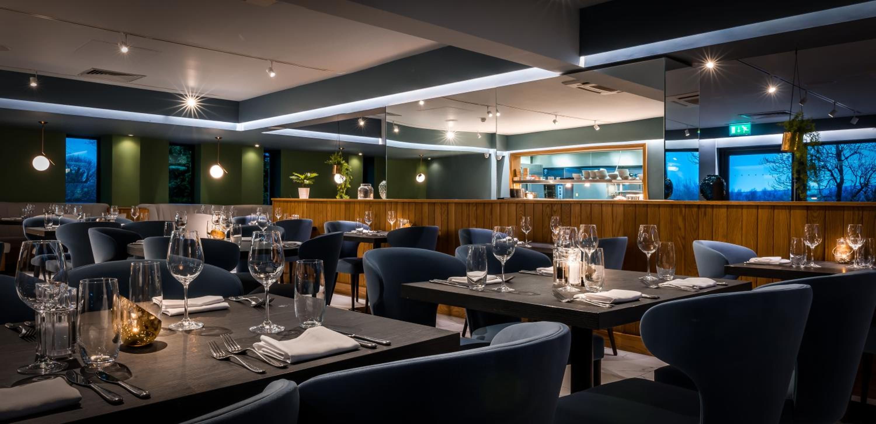Un interior de restaurante con varias mesas, sillas y una zona de bar.