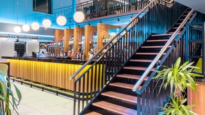 A modern interior with a wooden staircase, a bar area, and a seating area with potted plants. - Foxfields Country Hotel (Clitheroe)