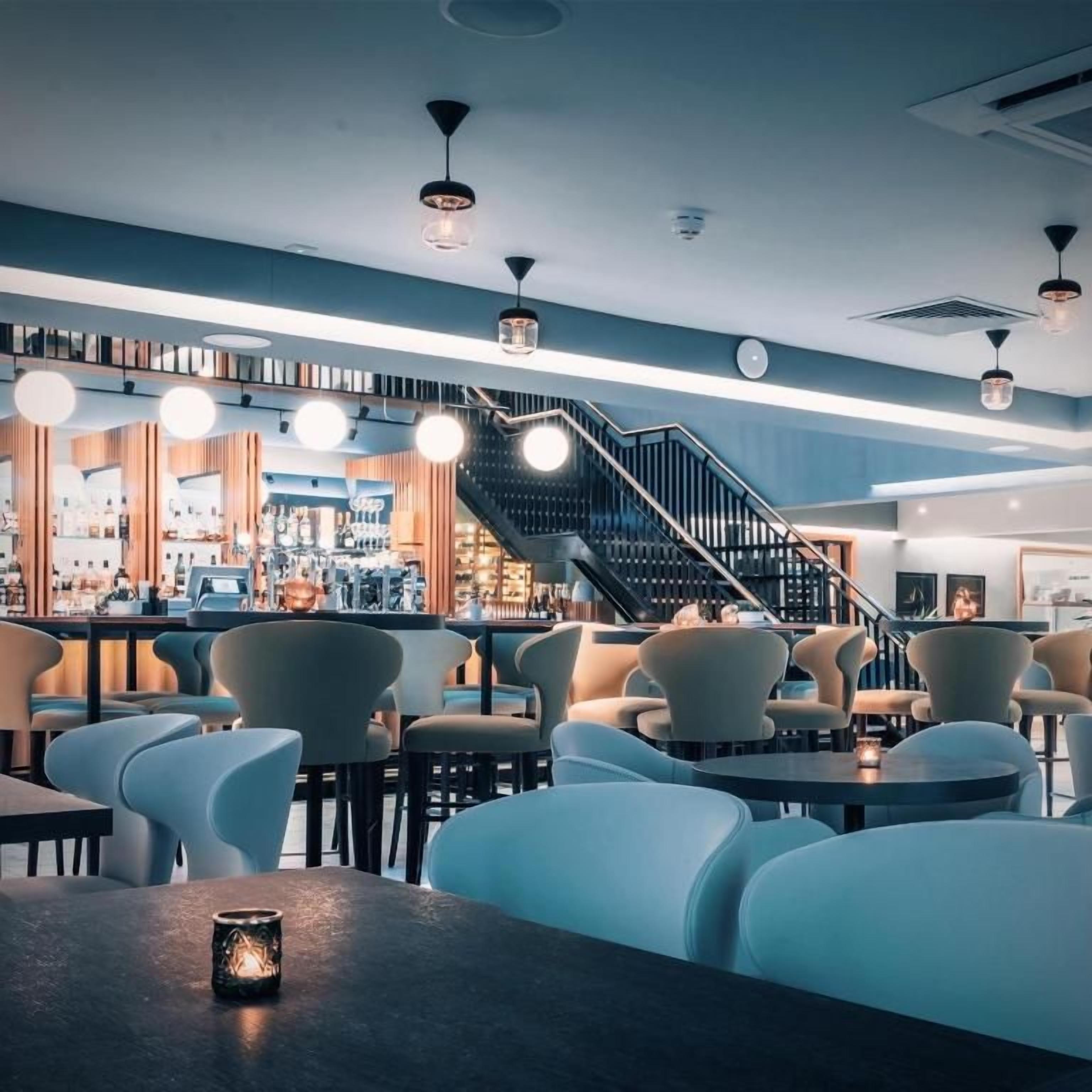 Zona de bar amb seients, una escala i un taulell amb diversos articles.