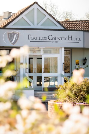 The exterior of Foxfields Country Hotel with a prominent entrance, a logo, and a sign indicating the establishment year.