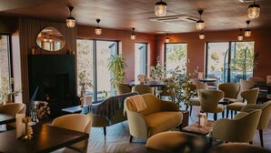A cozy restaurant with a fireplace, comfortable seating, and large windows offering views. - Foxfields Country Hotel (Clitheroe)