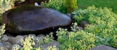 A garden with a pond, rocks, and a stone bench.
