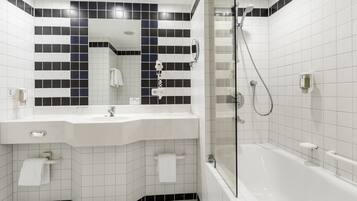 Un baño moderno con lavamanos, espejo y bañera blancos.