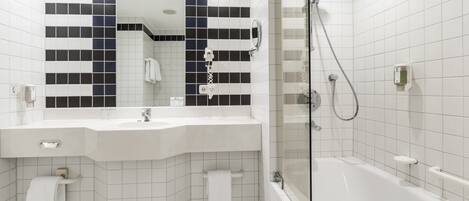 Un baño moderno con lavamanos, espejo y bañera blancos.