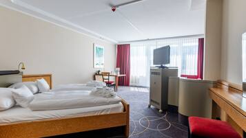 Een hotelkamer met twee bedden, een bureau, een stoel, een televisie en een badkamer.