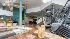A spacious lobby with a high ceiling, a staircase, and a hanging chair.