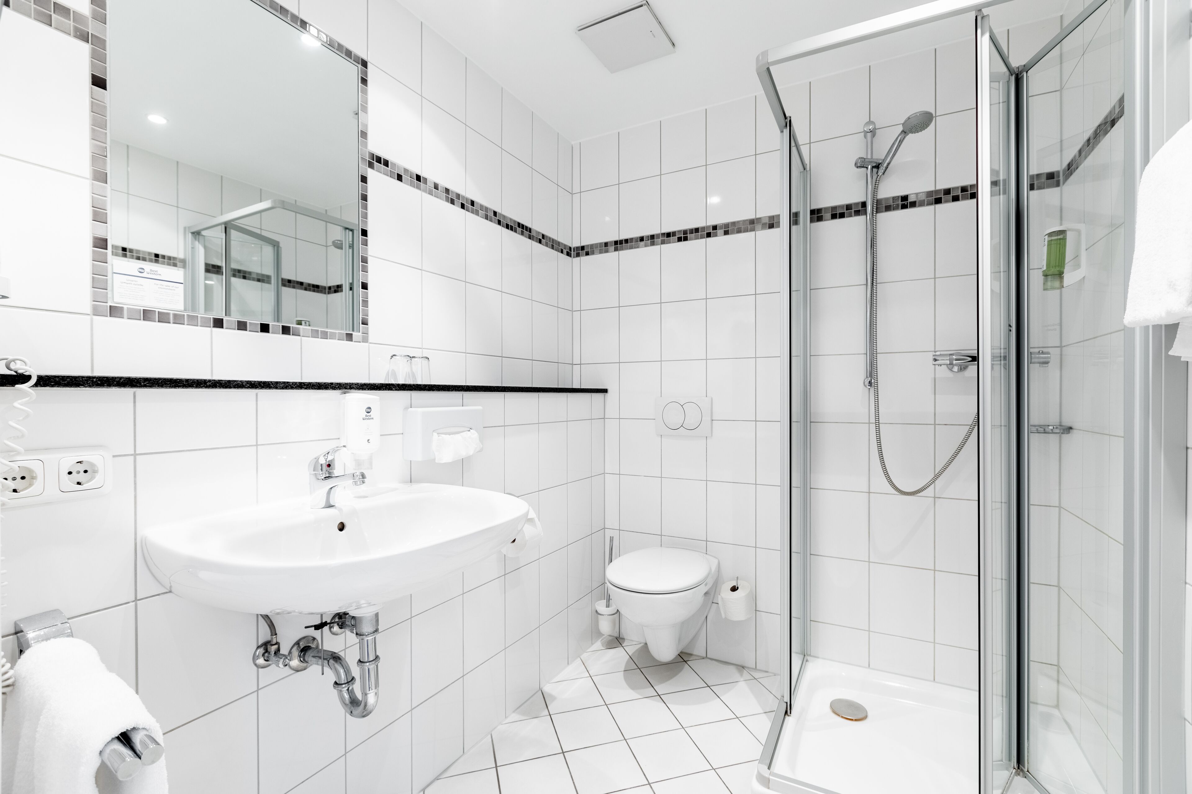 Een moderne badkamer met een wit wastafelmeubel, toilet en douchecabine.